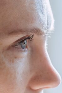 Side view closeup of crop lady with freckles and mascara applied on blue eyes