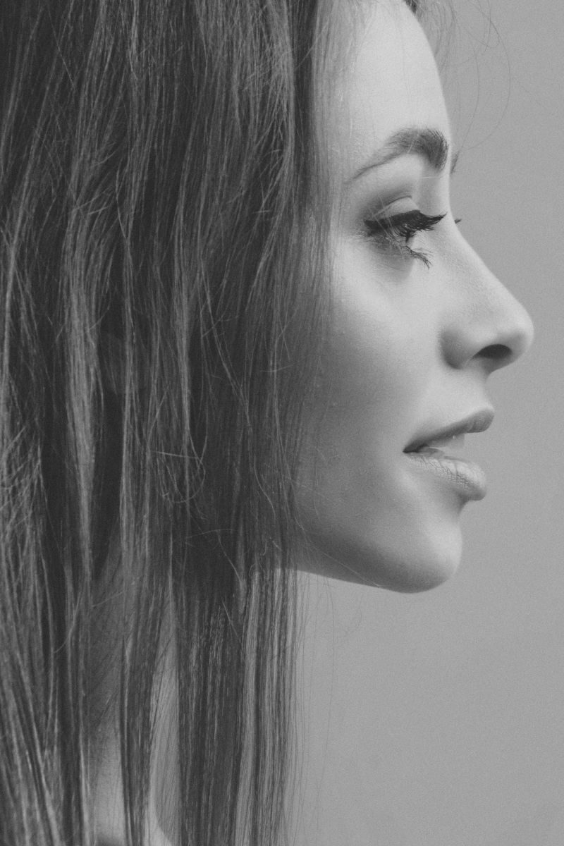 A black and white side profile portrait of a woman with elegant features and long hair.